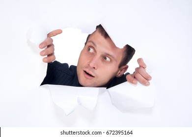 Young guy sticks his head through a hole in a sheet of paper