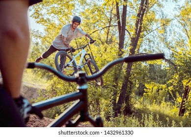 young guy with tattoos, biker, jumps and performs tricks on a bike. view through bicycle frame. in the forest against the setting sun. active lifestyle - Powered by Shutterstock