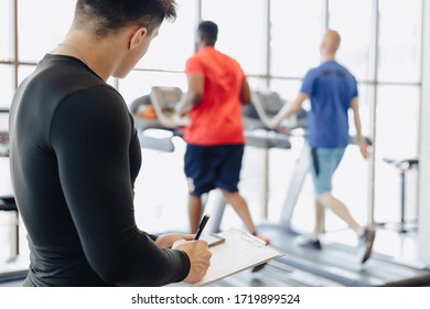 young guy trainer takes notes in the gym. personal trainer for sports. gym and sports.