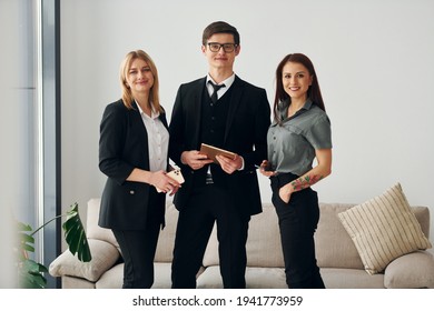 Young guy and two women in formal official clothes together indoors.
