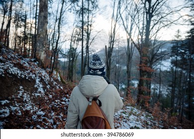 young guy in a warm cap and a jacket with a scarf on the neck, trousers and rubber boots walks alone in the Carpathian mountains with a  a backpack on his shoulders