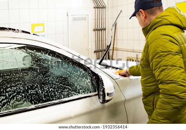 A\
young guy washes a car at a self-service car\
wash.
