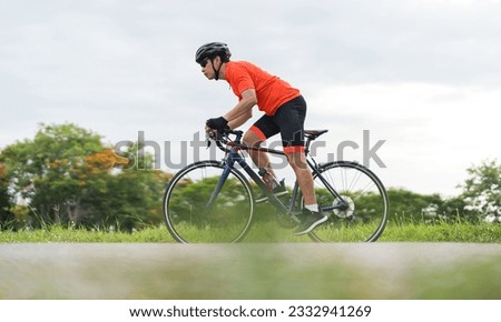Young guy wearing sport clothing, Cyclist pedaling on a racing bike outdoors in a sunny day, Sport activity on black bike