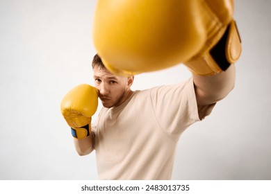 A young guy with yellow boxing gloves shows a punch. - Powered by Shutterstock