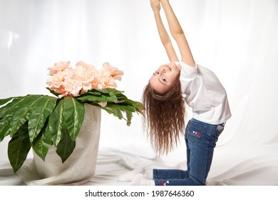 A Young Gymnast Girl With Flowers In The Studio. Teen Athlete Posing And Doing Sports Exercises On A White Background