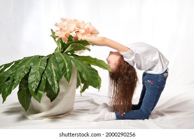 A Young Gymnast Girl With Flowers In The Studio. Teen Athlete Posing And Doing Sports Exercises On A White Background