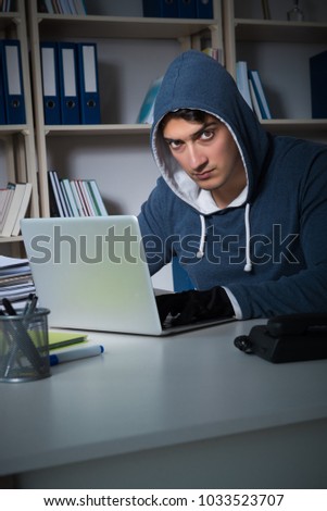 Young hacker hacking into computer at night