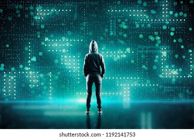 Young hacker in hoodie on abstract blurry circuit background. Hacking and computing concept.
