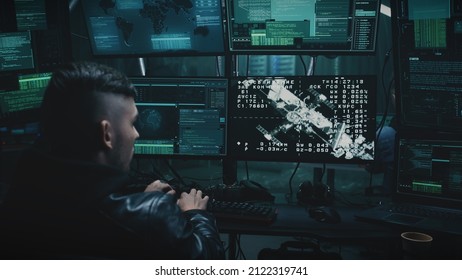 A Young Hacker At A Table With A Computer, Hacking Into The Docking Of The Space Module To The International Space Station. Footage On The Screeen Furnished By NASA.