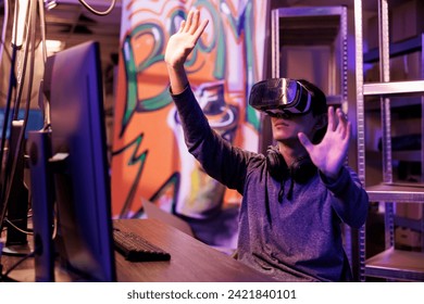 Young hacker using vr technology for hacking server and cracking password in metaverse. Man wearing virtual reality headset while breaking into secure system to steal confidential information