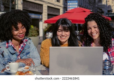 Young Haitian And Latina Businesswomen Together In An Outdoor Cafe Analyzing On A Laptop Computer