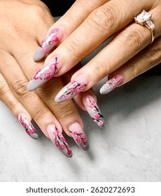 Young woman’s hand with long oval grey nails featuring cherry blossom design. Nail design. Manicure. Nail 2025. Acrylic