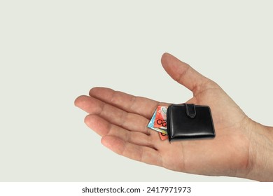 a young hand on a light background holding a purse showing devaluation of money or the shrinking value of money