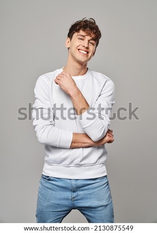 Young handome man smiling over gray background