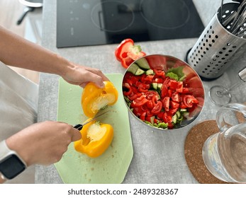 young hands cut yellow bell peppers on a green board while milking vegetable salad, a bowl with salad stands next to the girl - Powered by Shutterstock