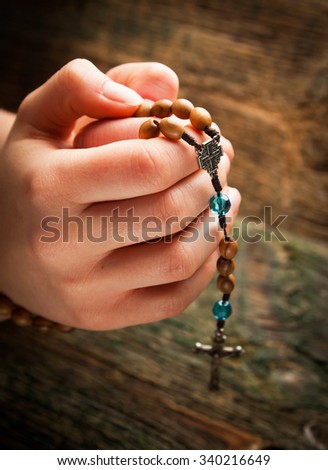 Young hands with wooden rosary 