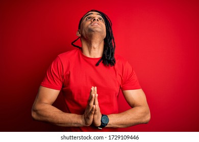 Young Handsome African American Afro Man With Dreadlocks Wearing Red Casual T-shirt Begging And Praying With Hands Together With Hope Expression On Face Very Emotional And Worried. Begging.