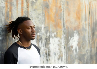 Young Handsome African American Black Male Outside Wearing A Black And White Baseball Jersey Henley Shirt With A Serious Look Face. Man With A Profile View Looking Off At The Future.