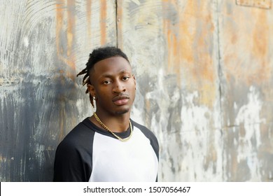 Young Handsome African American Black Male outside wearing a black and white baseball jersey henley shirt with a serious look face