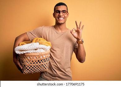 Young handsome african american man doing housework holding wicker basket with clothes doing ok sign with fingers, excellent symbol - Powered by Shutterstock