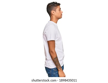 Young Handsome African American Man Wearing Casual White Tshirt Looking To Side, Relax Profile Pose With Natural Face With Confident Smile. 