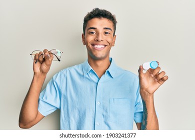 Young handsome african american man holding glasses and contact lenses smiling with a happy and cool smile on face. showing teeth. 