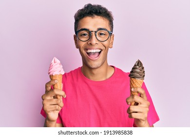 Young handsome african american man holding ice cream cones smiling and laughing hard out loud because funny crazy joke. 