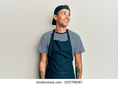 Young handsome african american man tattoo artist wearing professional uniform and gloves looking to side, relax profile pose with natural face and confident smile. 