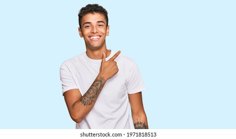 Young Handsome African American Man Wearing Casual White Tshirt Cheerful With A Smile Of Face Pointing With Hand And Finger Up To The Side With Happy And Natural Expression On Face 