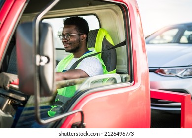 Young handsome African American man working in towing service and driving his truck.