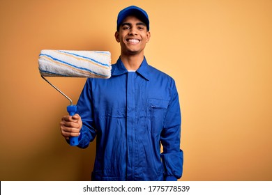 Young handsome african american painter man wearing uniform using painting roller with a happy face standing and smiling with a confident smile showing teeth