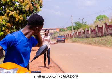 young handsome african biker making calls while waiting for his customer to arrive