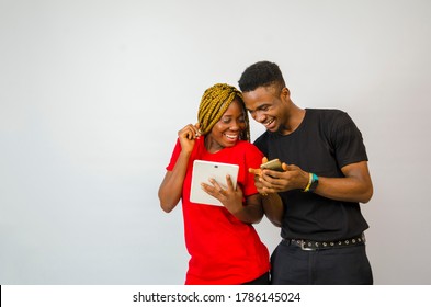 a young handsome african man and beautiful african lady isolated over white background both feeling highly excited about what they saw on their mobile phone