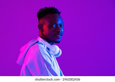 Young handsome African man with headphones in purple futuristic neon light studio background - Powered by Shutterstock