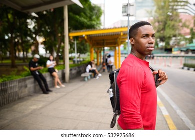 Young handsome African man waiting in bus stop at Bangkok city