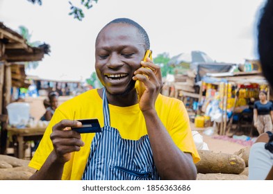 Young Handsome African Trader Feeling Excited As He Makes Call With Phone While Holding His Credit Card