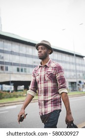 Young Handsome Afro Black Man Walking In The Street Of The City, Holding A Bag, Pensive - Thoughtful, Serious Concept