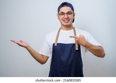Young handsome asian barista man wearing apron over white background showing product, pointing at something with hands. - Shutterstock ID 2160833585