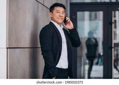 Young Handsome Asian Business Man In Black Suit Using Phone