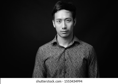 Young handsome Asian businessman against black background
