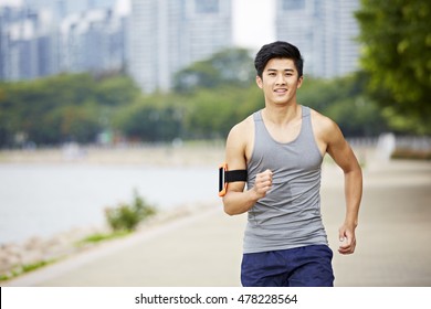 Young Handsome Asian Jogger Running Exercising In City Park Wearing Fitness Tracker