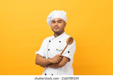 Joven y apuesto chef asiático con uniforme y sombrero sostiene utensilios de cuero cocinando en la cocina varios gestos de acción sobre aislado fondo amarillo. Hombres indios Ocupación chef restaurante y hotel.