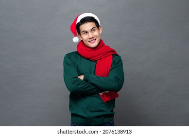 Young handsome Asian man in Christmas attire crossing arms and looking up in isolated gray color background - Powered by Shutterstock