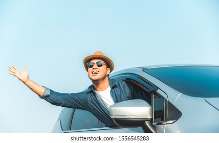 Young Handsome Asian Man Driving Car To Travel On His Holiday Vacation Time With Beautiful Blue Sky.