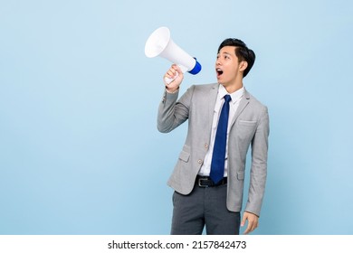 Young handsome Asian man in formal business suit holding megaphone and yelling in isolated light blue color studio background - Powered by Shutterstock