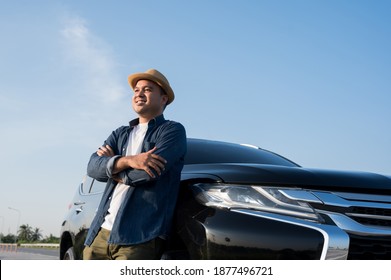 Young Handsome Asian Man Getting The New Car.He Standing With Arm Crossed In Front Of The Car.He Very Happy. Buy Or Rent A Car Concept.