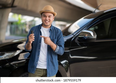 Young Handsome Asian Man Getting The New Car.He Showing Car Key And Very Happy. Buy Or Rent A Car Concept.