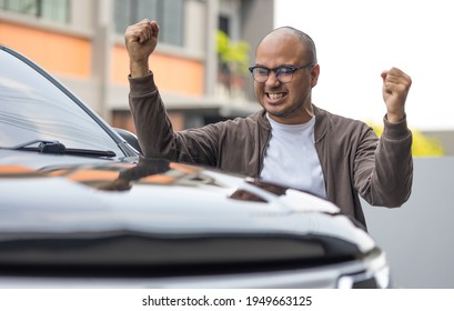 Young Handsome Asian Man Getting The New Car. He Very Happy And Excited Hand Stretch In The Air. Buy Or Rent Car Concept.