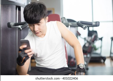 Young Handsome Asian Man Using Smart Phone In Modern Gym