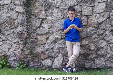 Young handsome Asian man using smartphone with his back against the stone wall